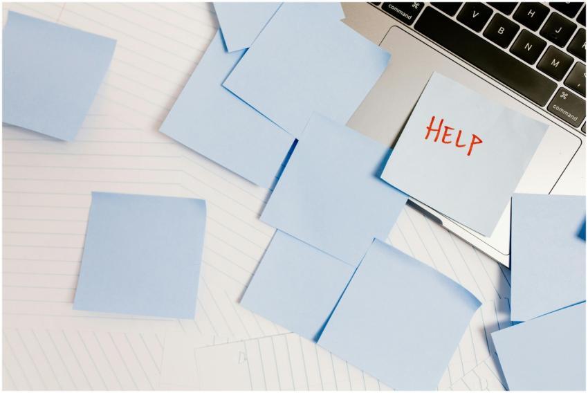 A cluttered workspace with sticky notes on a lapto