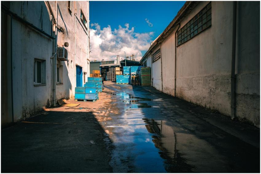 Deserted industrial alley with reflections of blue