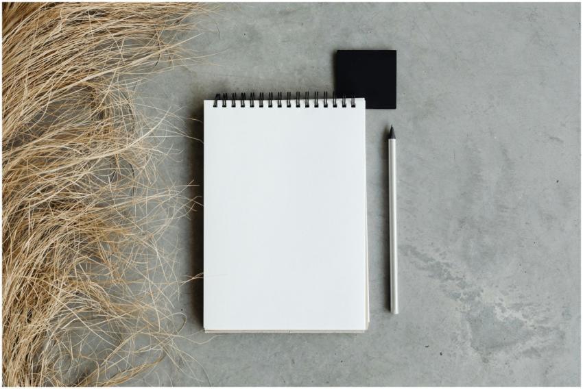 Flat lay of a notepad and pencil on a concrete sur