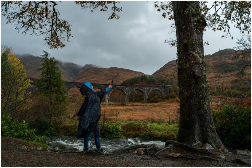 Person in raincoat near famous viaduct with scenic