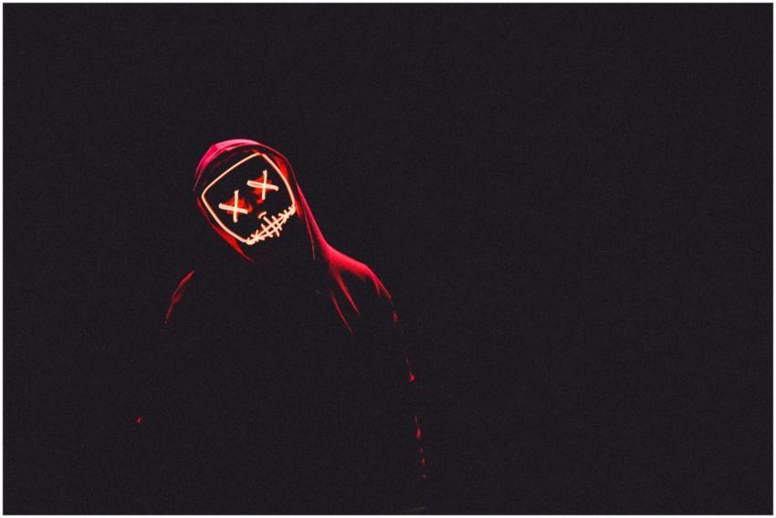 A mysterious figure in a glowing neon mask and dar