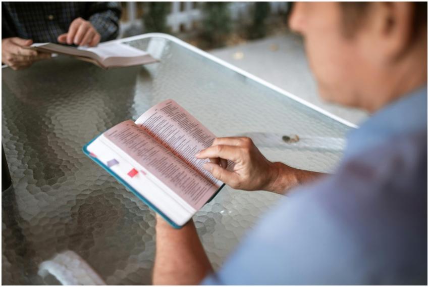 Two adults engaged in Bible study at a glass table