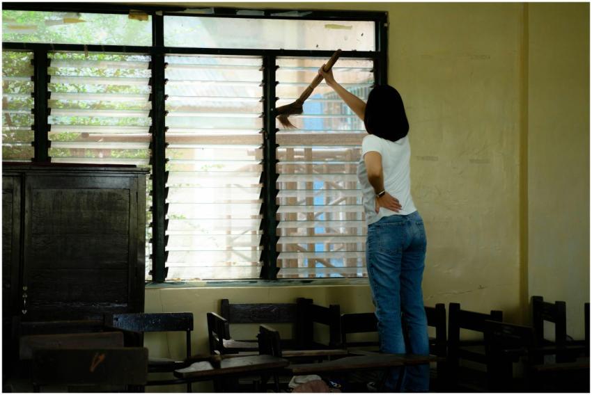 A woman cleaning a classroom window, enhancing the