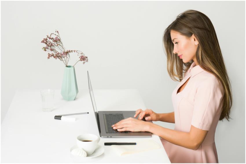 A woman in a pink dress working on a laptop at a m