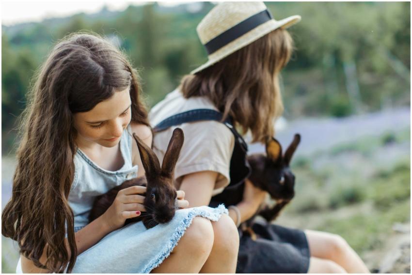 Two young girls enjoying outdoor time with pet rab