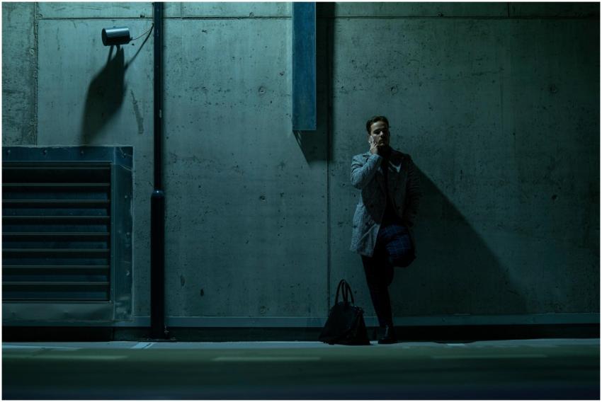 Businessman on phone next to a concrete wall in di