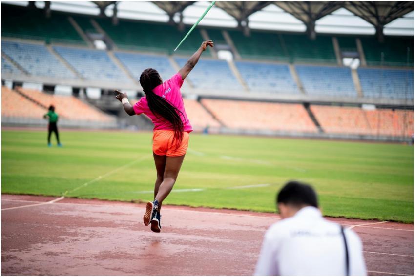 Female athlete in action throwing javelin at a sta