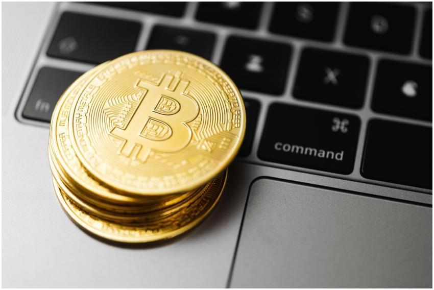 Close-up of gold bitcoin coins on a laptop keyboar