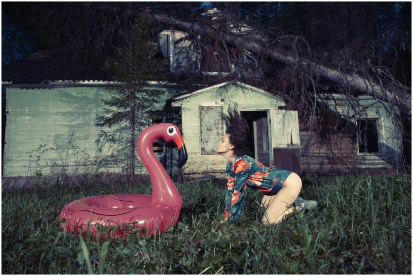A woman poses beside an inflatable flamingo in fro
