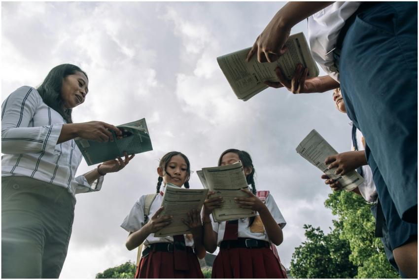 Students and teacher in school uniforms reading bo