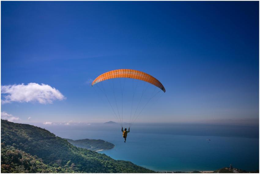 A lone paraglider flies over the ocean with a brea