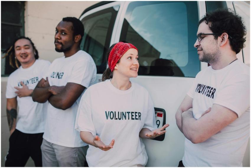 Four volunteers interacting by a van, promoting co