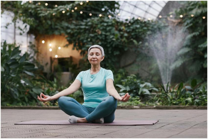 Elderly woman meditating in serene botanical garde