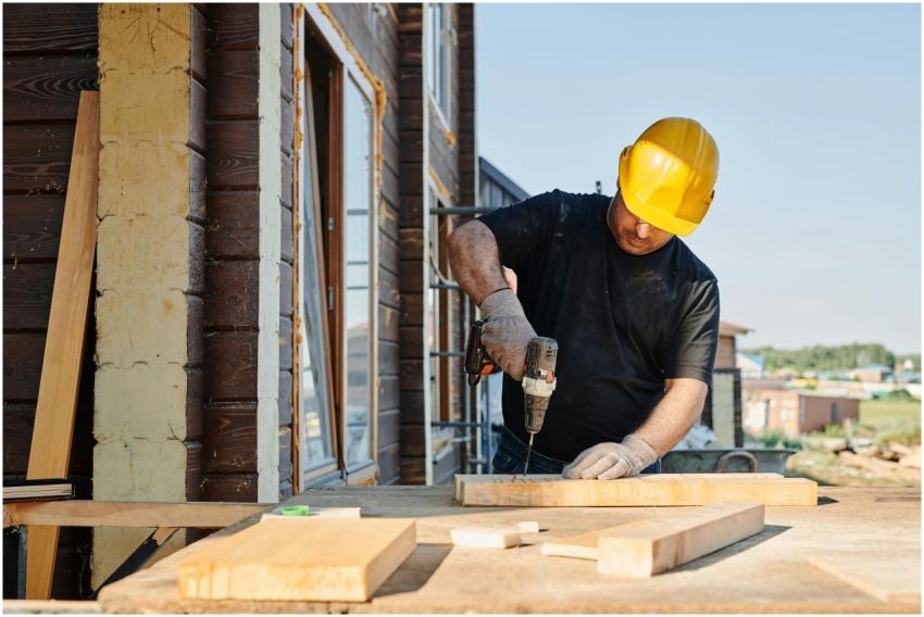 A construction worker using a power drill on a bui