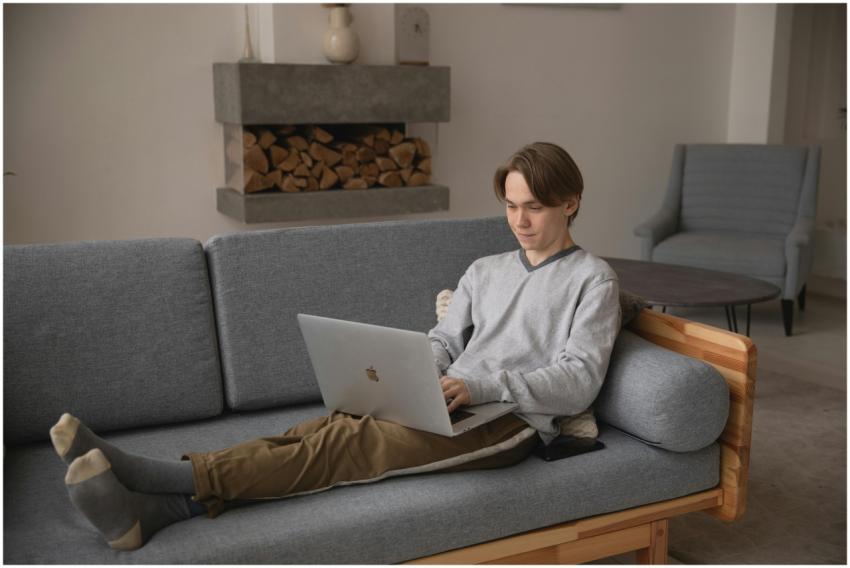 A young man comfortably working on a laptop at hom