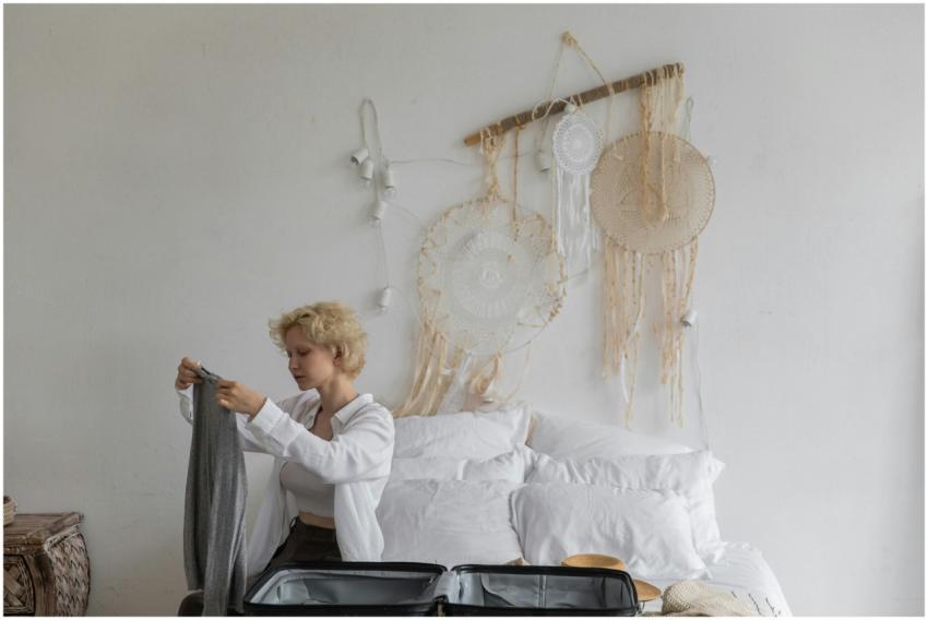 A young woman carefully packs a suitcase in a bohe