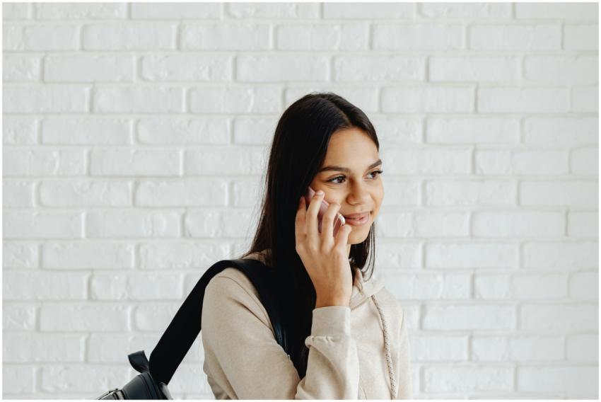 Smiling teen girl in a hoodie, talking on the phon