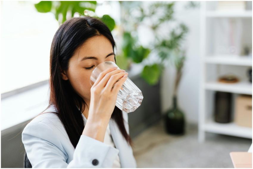 Adult woman sipping water from a glass in a modern