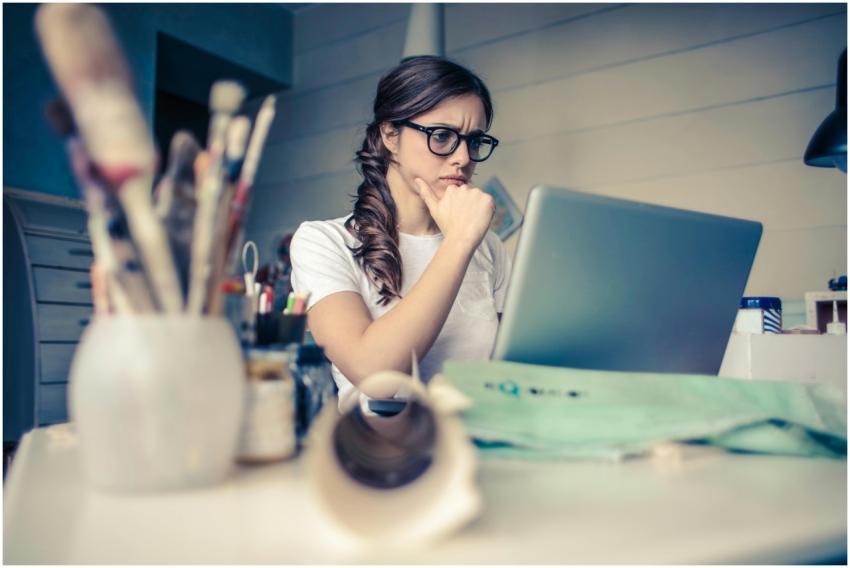 Young woman with glasses deeply focused on a lapto