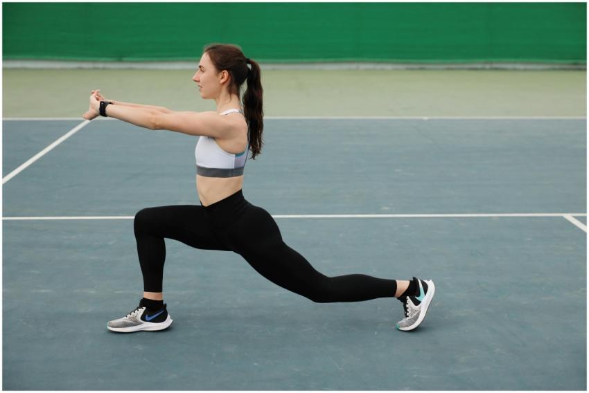 Woman in activewear stretching on a tennis court,