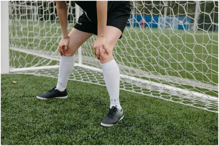 Soccer player resting in front of the goal on a gr
