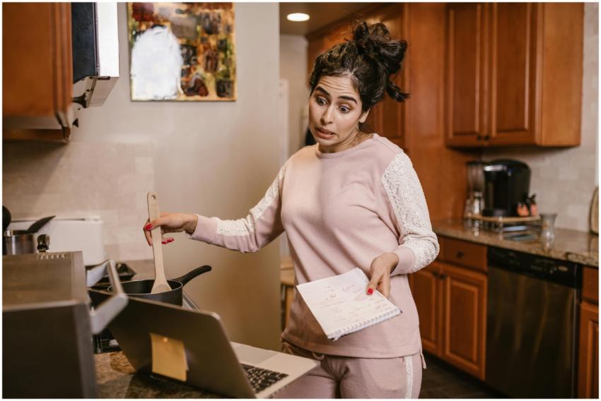 Woman multitasking in her kitchen with a laptop an