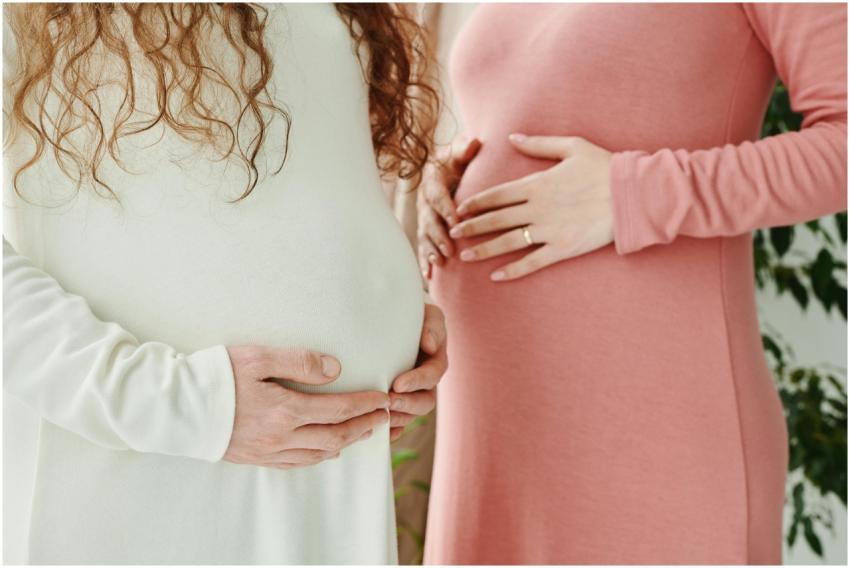 Two expectant women gently holding their pregnant