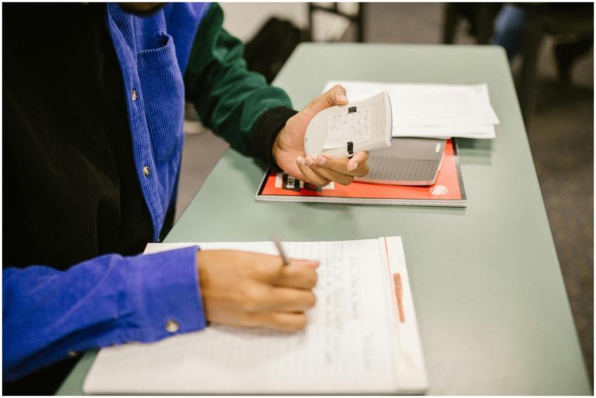 Student using a calculator and taking notes during