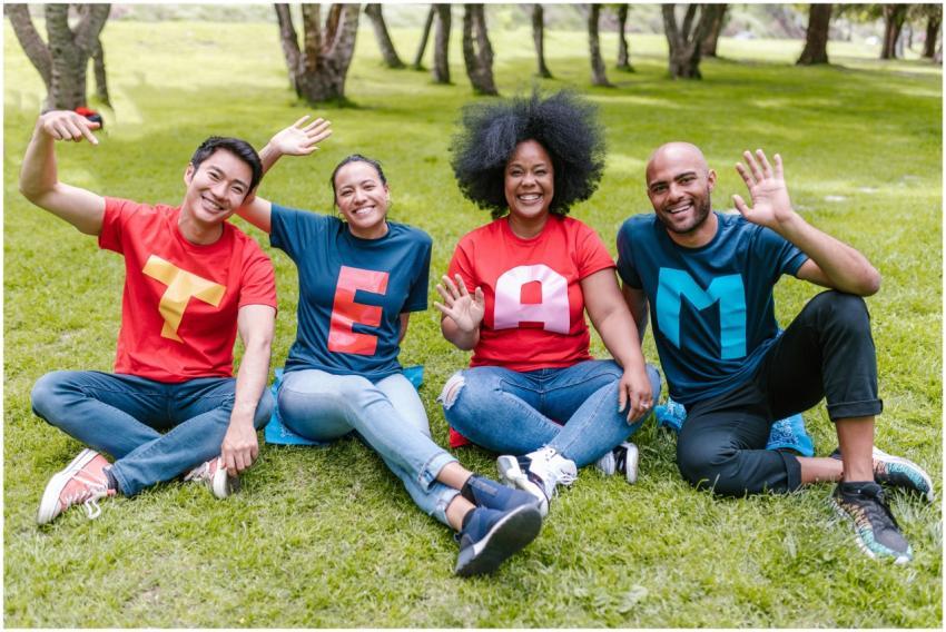 Multiracial team sitting on grass in park, wearing
