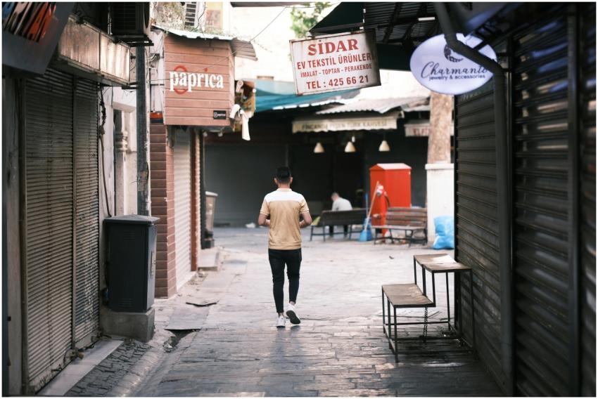 A lone man strolls down a quiet, narrow bazaar str