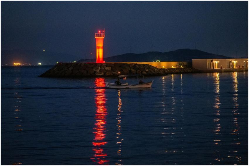 Serene night view of a red lighthouse and motorboa