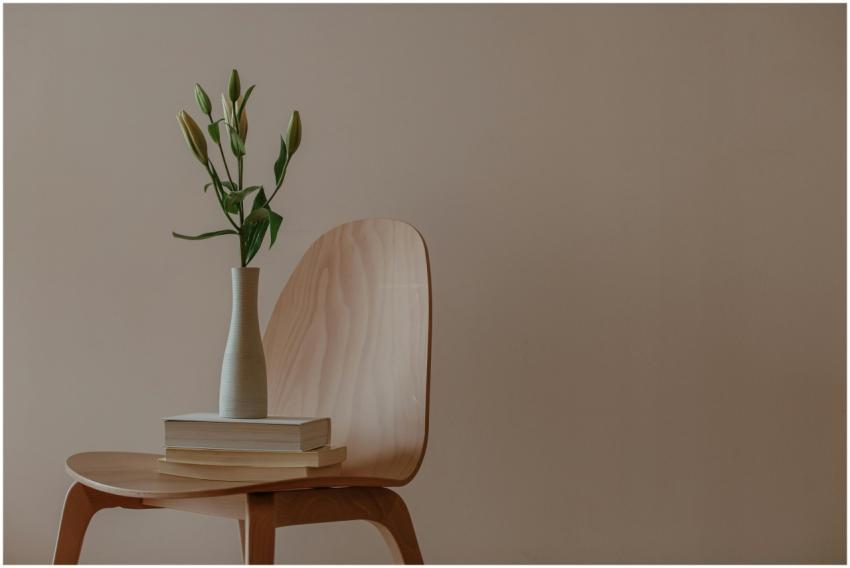 A minimalist setup with a wooden chair, vase, and
