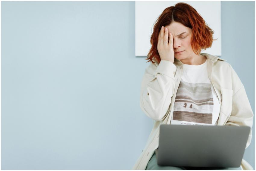 A woman experiencing stress, seated with a laptop,