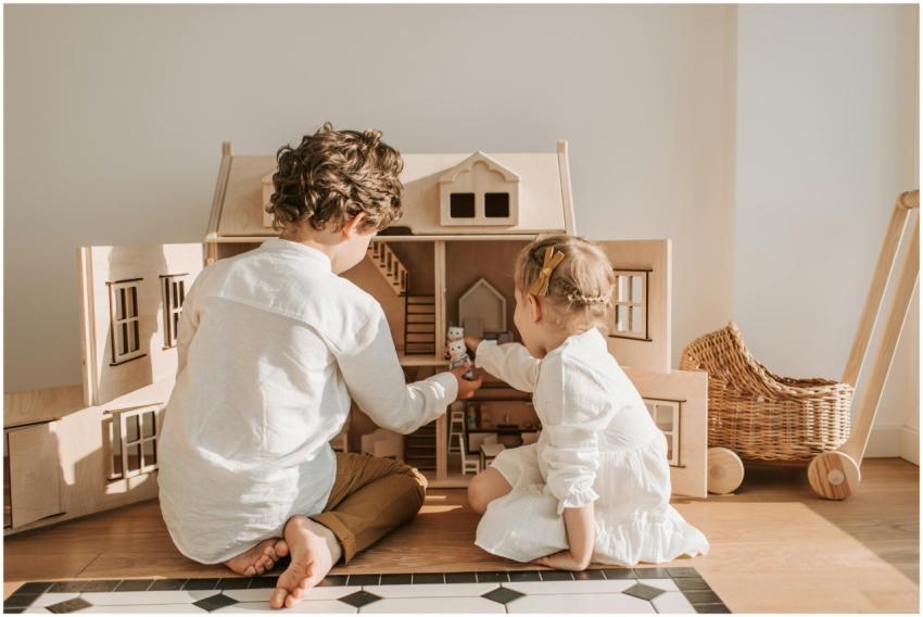 Two children enjoy playing with a wooden dollhouse