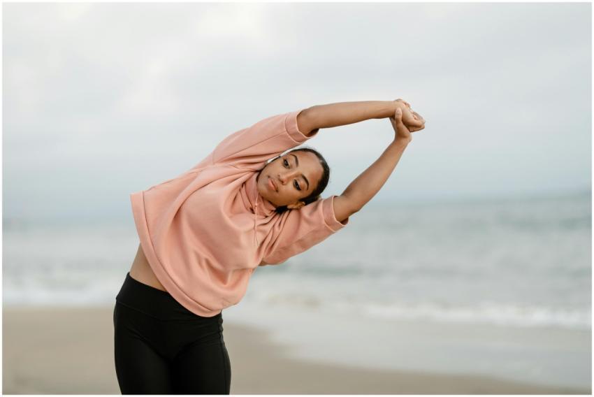 A woman performs a side stretch yoga pose on an oc