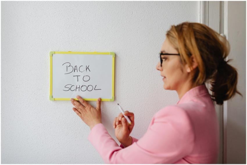 A teacher in pink blazer writing 'Back to School'