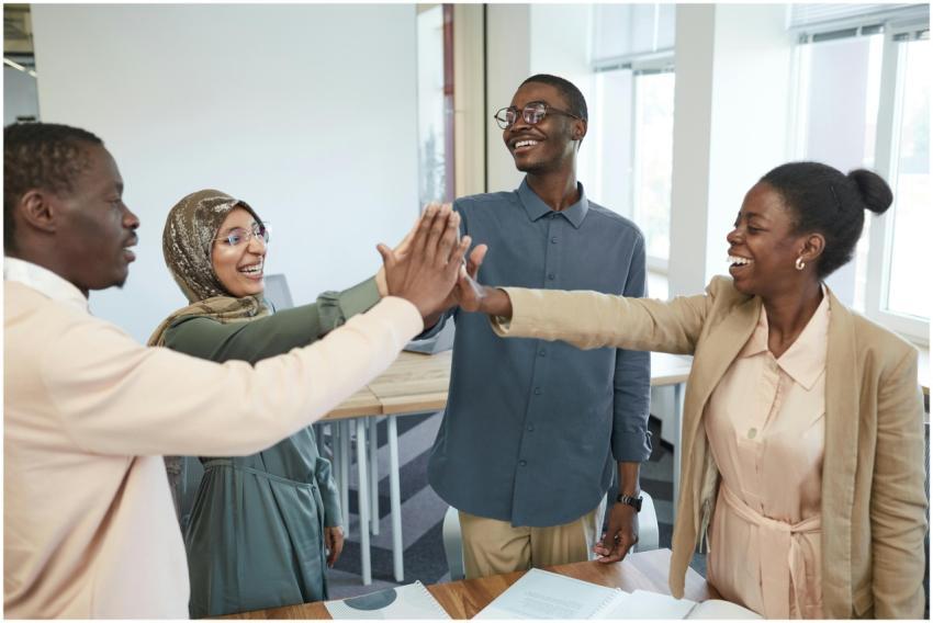 A joyful group of diverse colleagues high-fiving e
