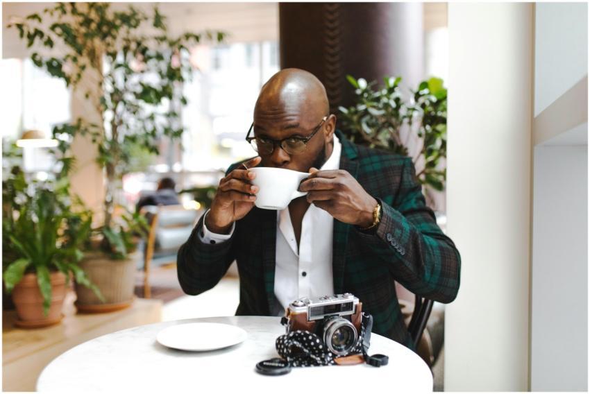 A man sipping coffee in a cafe with a vintage came