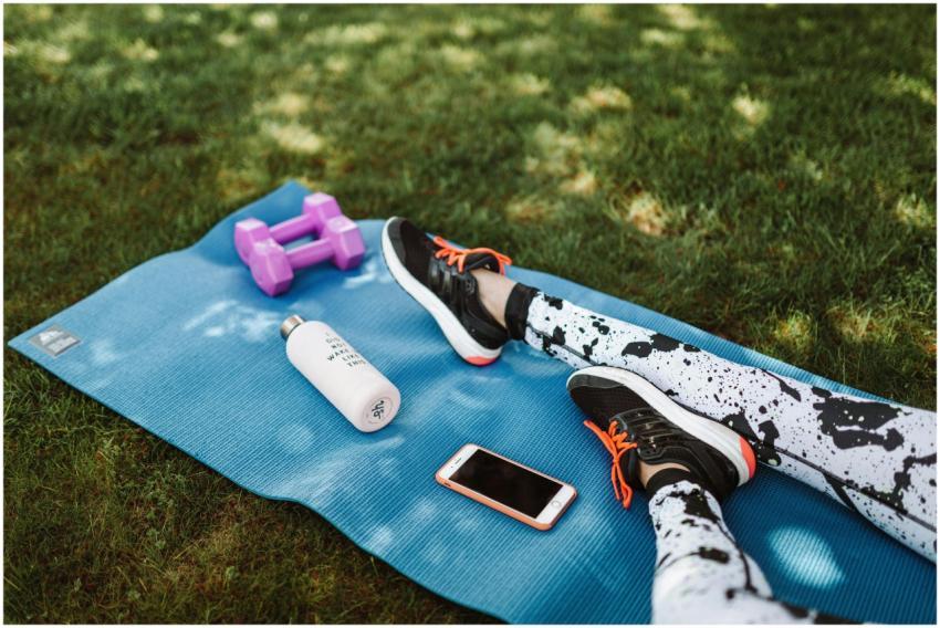 Focused workout setup outdoors with mat, dumbbells