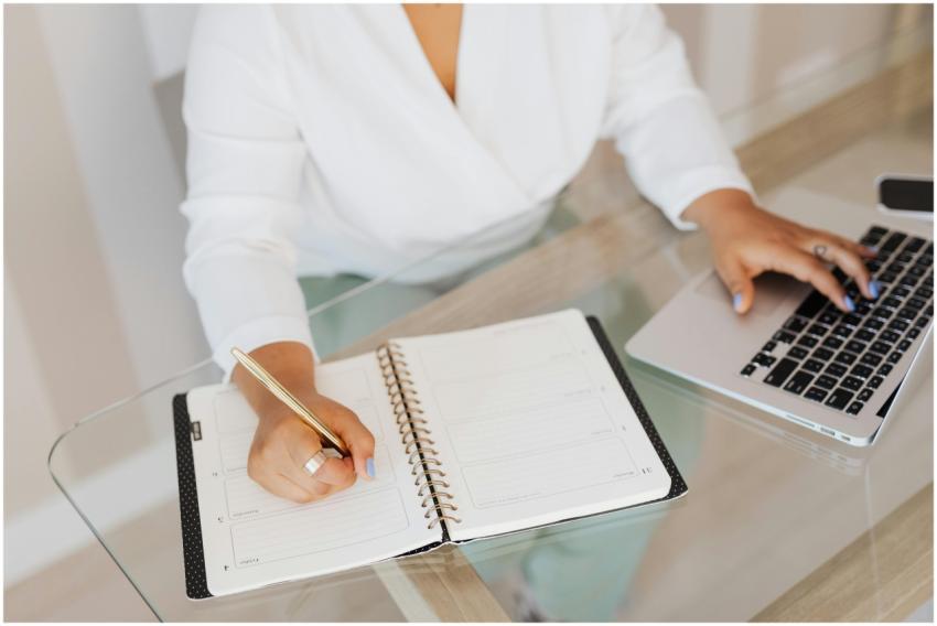 A person planning and typing on a laptop at a glas