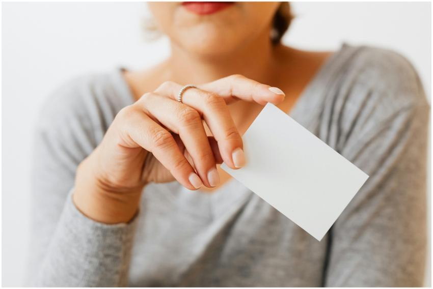 A woman in gray sleeves holding a blank business c