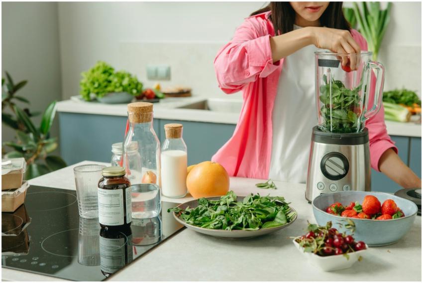 Woman in pink sleeve blending fresh fruits and veg