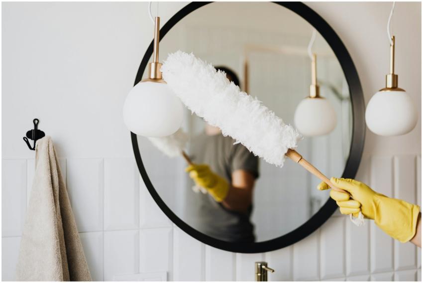 A person cleaning an elegant bathroom mirror with