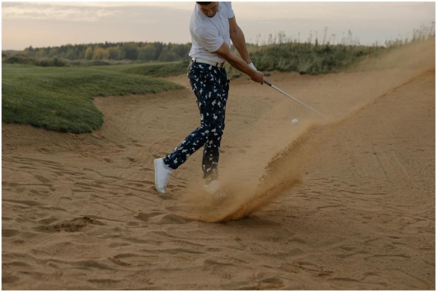 A golfer in a sand trap skillfully hits the ball o
