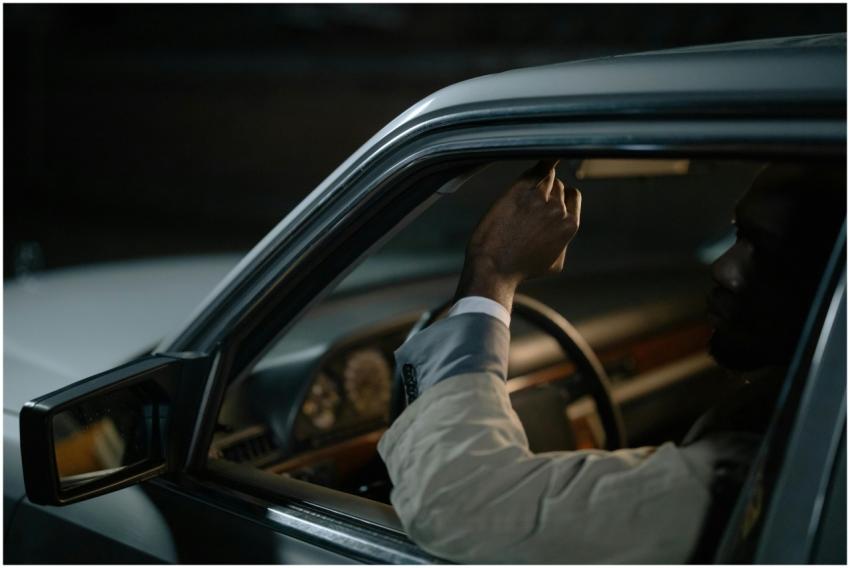 Man inside a car adjusting the rearview mirror in