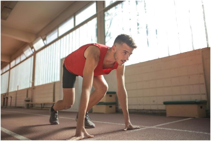 Focused male athlete in starting position indoors,