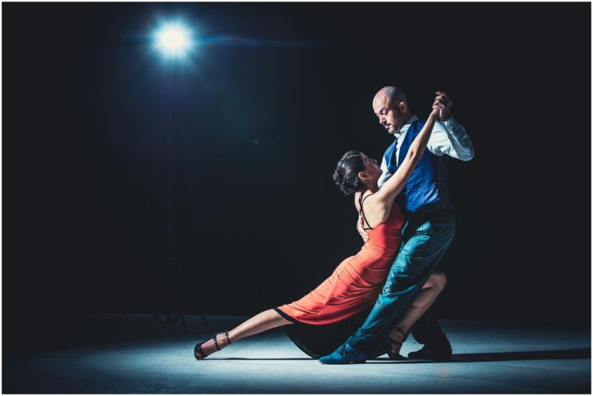Elegant couple performing tango under a dramatic s