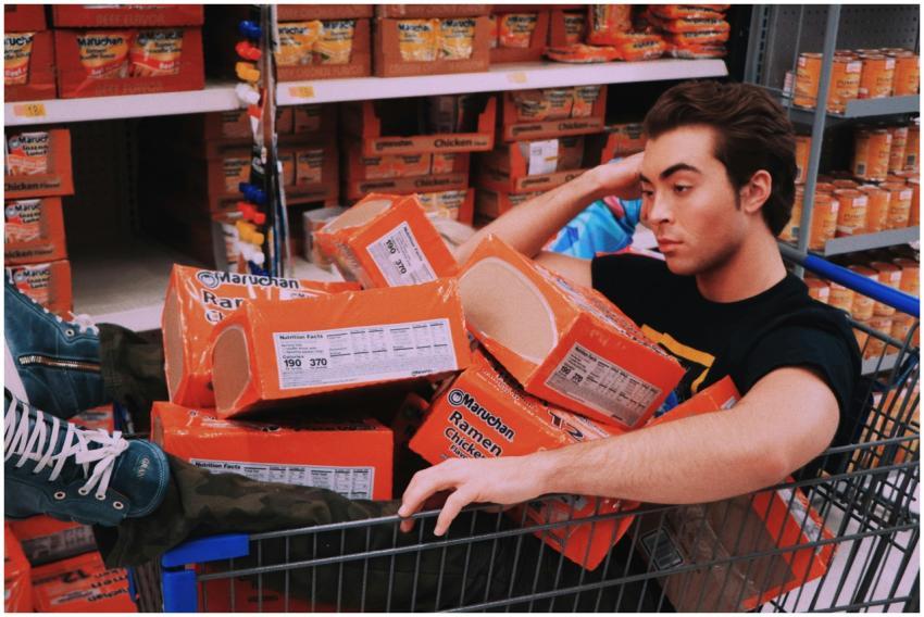 A man lounging in a shopping cart filled with Maru