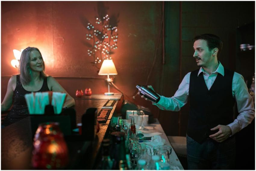 A bartender prepares a cocktail for a woman at a s