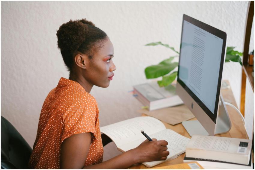 A focused young woman studying with books and a co